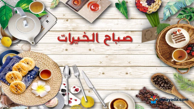 طاولة إفطار خشبية عليها شاي وقهوة ومعجنات وحلوى مع عبارة صباح الخيرات.